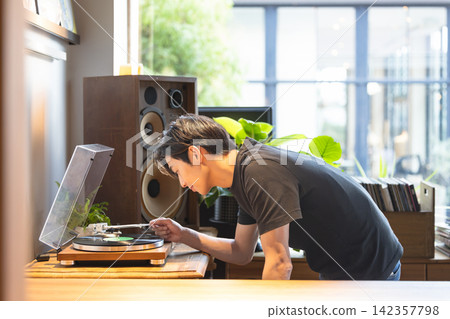 A man enjoying music while operating a record player. A man enjoying music while operating a record player. 142357798