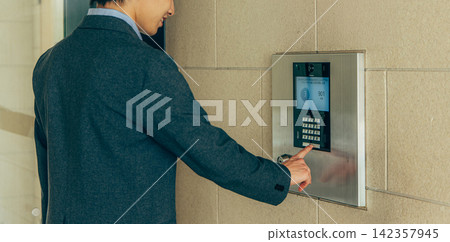 一名男子按下公寓大樓的對講機。 142357945
