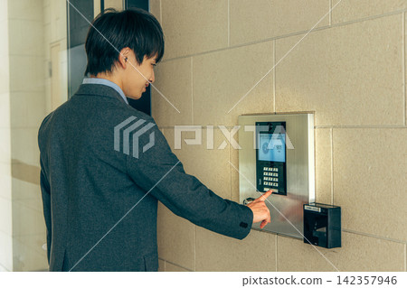 一名男子按下公寓大樓的對講機。 142357946