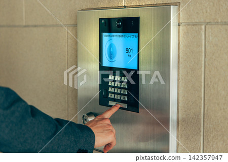 一名男子按下公寓大樓的對講機。 142357947