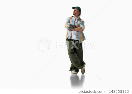 Man crosses arms in striped shirt and oversized green trousers Man crosses arms in striped shirt and oversized green trousers 142358553