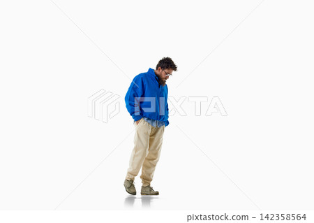 Stylish man looks down in blue knitwear and loose cream trousers 142358564