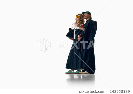 Stylish couple poses together in coordinated dark layered outfits Stylish couple poses together in coordinated dark layered outfits 142358589