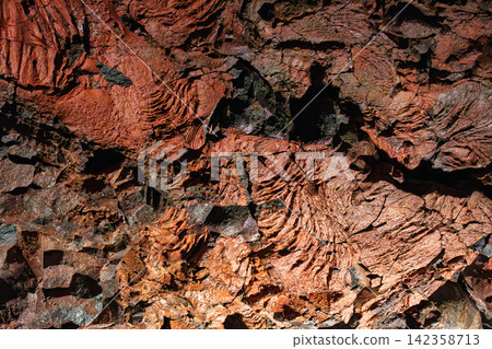 Cooled lava layering black ripples around a reddish core, Raufarholshellir, Iceland 142358713