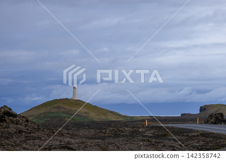 Reykjanes Lighthouse on a rounded hill above a gravel road, Iceland, in muted evening daylight Reykjanes Lighthouse on a rounded hill above a gravel road, Iceland, in muted evening daylight 142358742