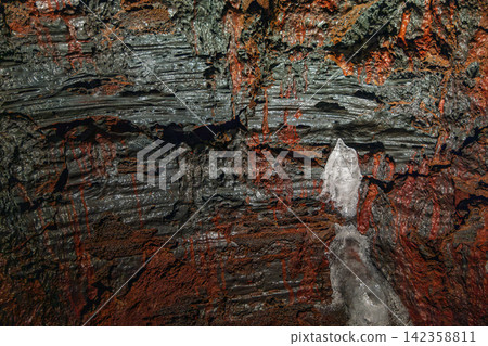 Cooled lava mixing grey ropy folds with small ice crystals, Raufarholshellir, Iceland Cooled lava mixing grey ropy folds with small ice crystals, Raufarholshellir, Iceland 142358811