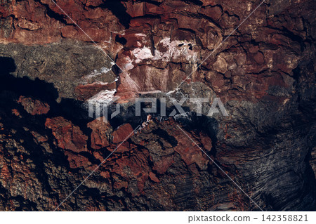 Cooled lava twisting across a broad iron-red cave surface, Raufarholshellir, Iceland Cooled lava twisting across a broad iron-red cave surface, Raufarholshellir, Iceland 142358821