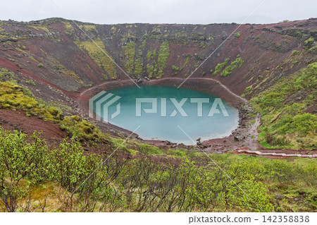 Wet scoria slopes descending toward turquoise water at Kerid Crater, Iceland Wet scoria slopes descending toward turquoise water at Kerid Crater, Iceland 142358838