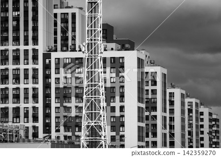 Black and white urban apartment buildings with construction crane and dramatic cloudy sky Black and white urban apartment buildings with construction crane and dramatic cloudy sky 142359270