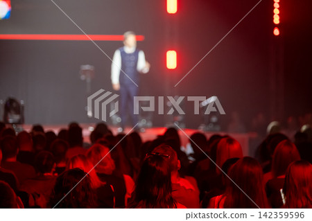 Audience listening to a blurred speaker during conference 142359596