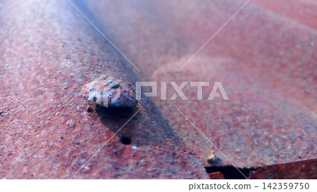 Rusty roofing nails on corrugated metal sheets. Rusty roofing nails on corrugated metal sheets. 142359750
