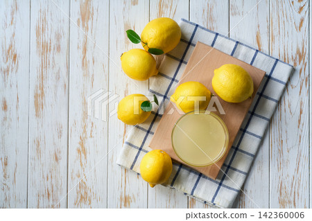 homemade lemon juice in glass and ripe lemons on white wooden table, with copy space for text. Top vie homemade lemon juice in glass and ripe lemons on white wooden table, with copy space for text. Top vie 142360006