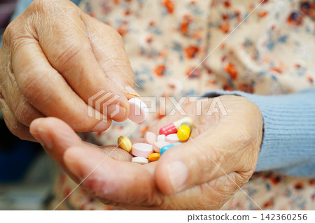 Asian elderly woman holding pill drug in hand, strong healthy medical. Asian elderly woman holding pill drug in hand, strong healthy medical. 142360256