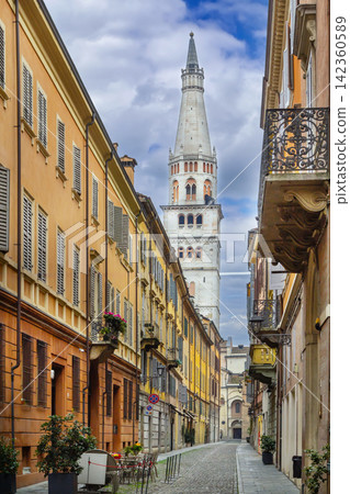 Narrow street in the historic center of Modena, Italy. View of the Ghirlandina bell tower and sunny architecture Narrow street in the historic center of Modena, Italy. View of the Ghirlandina bell tower and sunny architecture 142360589