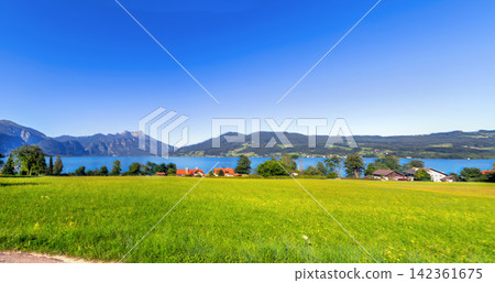 Panoramic view of Attersee lake in Upper Austria region. Clear turquoise water and mountains under bright summer sky Panoramic view of Attersee lake in Upper Austria region. Clear turquoise water and mountains under bright summer sky 142361675