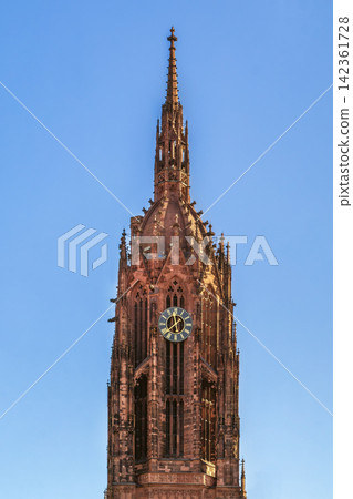 Tower of Frankfurt Cathedral from Main river in Germany. Gothic architecture detail in daylight under blue sky Tower of Frankfurt Cathedral from Main river in Germany. Gothic architecture detail in daylight under blue sky 142361728