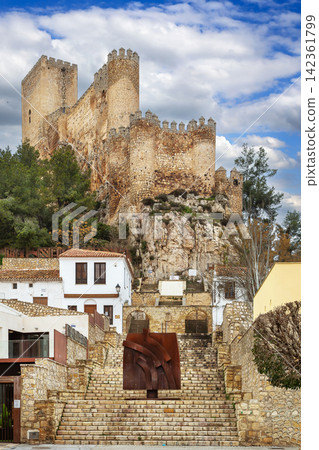 View of Almansa Castle from stone stairs in Albacete province, Spain. Medieval fortress architecture under cloudy sky in daytime View of Almansa Castle from stone stairs in Albacete province, Spain. Medieval fortress architecture under cloudy sky in daytime 142361799