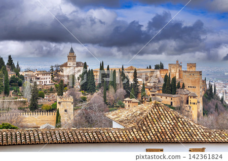 Ancient towers of Alhambra seen from lush Generalife gardens in Granada, Spain. Soft natural light under cloudy overcast sky Ancient towers of Alhambra seen from lush Generalife gardens in Granada, Spain. Soft natural light under cloudy overcast sky 142361824