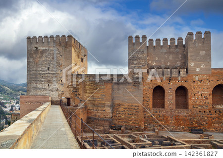 Inner walls and fortifications of Alcazaba fortress in Granada, Spain. Ancient stone architecture under cloudy overcast sky Inner walls and fortifications of Alcazaba fortress in Granada, Spain. Ancient stone architecture under cloudy overcast sky 142361827