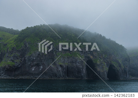 Japan - A view of the mist-shrouded coastline and cliffs of the Shiretoko Peninsula from a Shiretoko cruise in Shari Town, Hokkaido. Japan - A view of the mist-shrouded coastline and cliffs of the Shiretoko Peninsula from a Shiretoko cruise in Shari Town, Hokkaido. 142362183