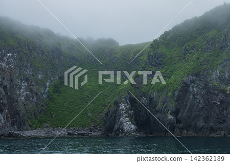 Japan - A view of the mist-shrouded coastline and cliffs of the Shiretoko Peninsula from a Shiretoko cruise in Shari Town, Hokkaido. Japan - A view of the mist-shrouded coastline and cliffs of the Shiretoko Peninsula from a Shiretoko cruise in Shari Town, Hokkaido. 142362189
