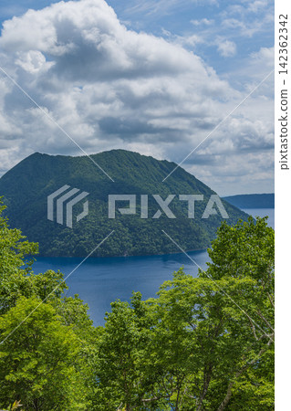 日本北海道清裡町的摩週湖,在初夏晴朗的天空下,四周綠樹環繞。 日本北海道清裡町的摩週湖,在初夏晴朗的天空下,四周綠樹環繞。 142362342