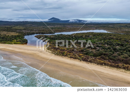 Aerial view of Lake Arragan Beach and Lake Arragan within Yuraygir National Park, showcasing the sandy Pacific coastline, coastal lake, native bushland and surrounding natural landscape on the NSW Aerial view of Lake Arragan Beach and Lake Arragan within Yuraygir National Park, showcasing the sandy Pacific coastline, coastal lake, native bushland and surrounding natural landscape on the NSW 142363030