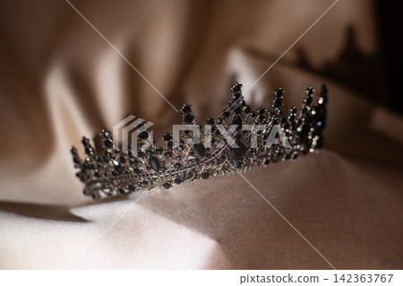 Elegant Black Crystal Crown, Tiara on Beige Gold Fabric. Elegant Black Crystal Crown, Tiara on Beige Gold Fabric. 142363767