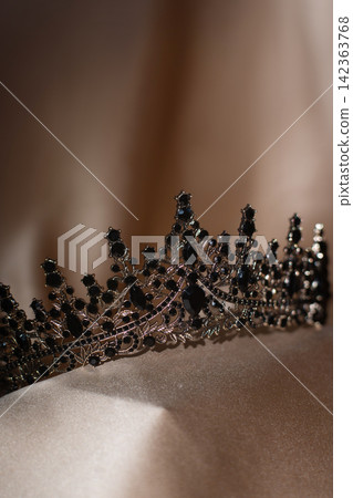 Elegant Black Crystal Crown, Tiara on Beige Gold Fabric. Elegant Black Crystal Crown, Tiara on Beige Gold Fabric. 142363768