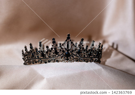 Elegant Black Crystal Crown, Tiara on Beige Gold Fabric. Elegant Black Crystal Crown, Tiara on Beige Gold Fabric. 142363769