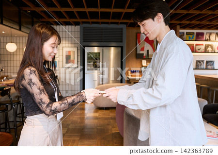一對年輕的商務人士，一男一女，在時尚的辦公室交換名片。 142363789