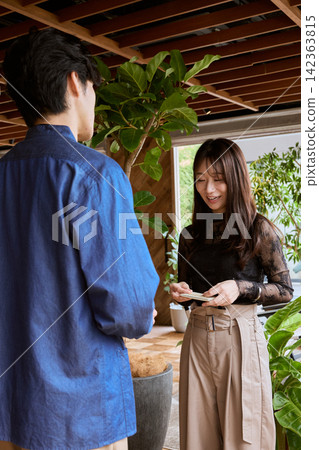 一對年輕的商務人士,一男一女,在時尚咖啡館交換名片。 一對年輕的商務人士,一男一女,在時尚咖啡館交換名片。 142363815