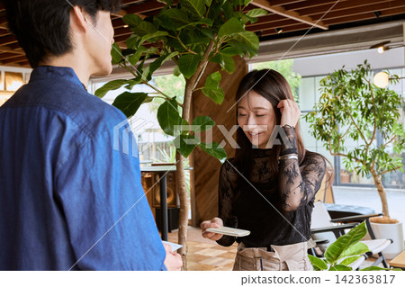 一對年輕的商務人士,一男一女,在時尚咖啡館交換名片。 一對年輕的商務人士,一男一女,在時尚咖啡館交換名片。 142363817