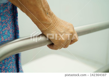 Asian elderly woman patient use toilet support rail in bathroom. Asian elderly woman patient use toilet support rail in bathroom. 142364387