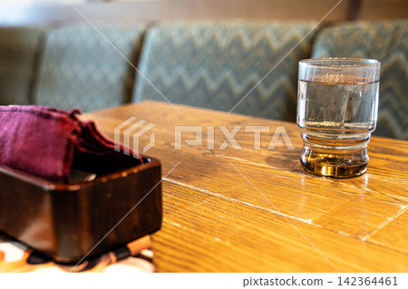 A clear glass of water and a copy space on a wooden restaurant table. A clear glass of water and a copy space on a wooden restaurant table. 142364461