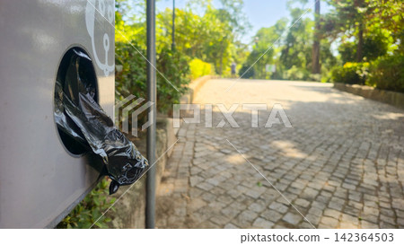 A close-up of dog waste bags in a public park in Portugal. Concepts include animal waste, public order, responsible use, and eco-friendliness. 142364503