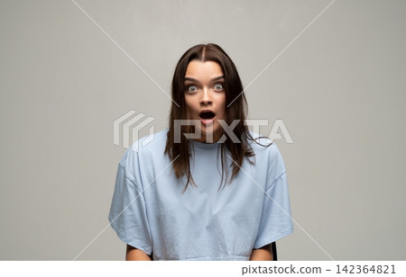 Young woman reacting with wide eyes and open mouth, expressing surprise, shock, disbelief, and excitement Young woman reacting with wide eyes and open mouth, expressing surprise, shock, disbelief, and excitement 142364821