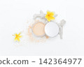Soft powder spills from open container beside mirror. Yellow flowers add bright tropical flair. White coral fragment accents the clean minimalist scene. Ideal for beauty, skincare 142364977