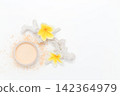Soft powder spills from open container beside mirror. Yellow flowers add bright tropical flair. White coral fragment accents the clean minimalist scene. Ideal for beauty, skincare 142364979