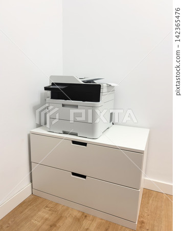 Laser printer on a white drawer cabinet in a home office corner Laser printer on a white drawer cabinet in a home office corner 142365476