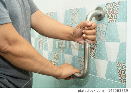 Asian elderly woman patient use handrail safety in toilet support rail in bathroom. Asian elderly woman patient use handrail safety in toilet support rail in bathroom. 142365889