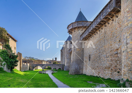 Courtyard of Cite de Carcassonne in France, view along the wall facing the bridge. Medieval fortress architecture in daylight 142366047