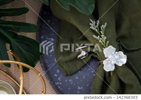 couple wedding rings put together with in napkins on the reception table decoration with flower and leaf couple wedding rings put together with in napkins on the reception table decoration with flower and leaf 142366303
