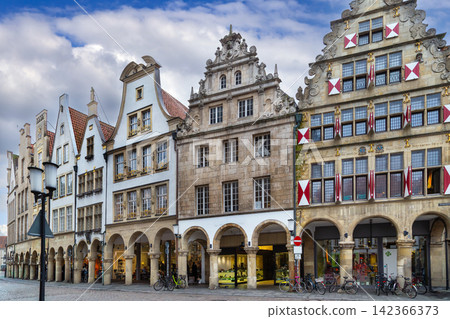 Prinzipalmarkt, Munster, Germany, view of houses along street. Historic gabled facades and arcades under cloudy daytime sky Prinzipalmarkt, Munster, Germany, view of houses along street. Historic gabled facades and arcades under cloudy daytime sky 142366373