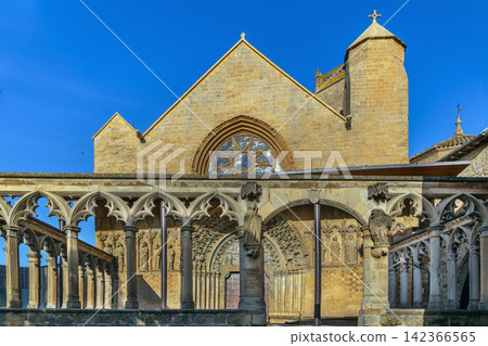Church of Santa Maria la Real in Olite, Spain, facade view. Gothic architecture with historic stone fence in foreground Church of Santa Maria la Real in Olite, Spain, facade view. Gothic architecture with historic stone fence in foreground 142366565