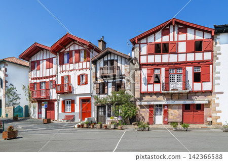 Street with historical basque houses in Ainhoa, France. Eye level exterior view. Sunny day with clear blue sky. Old village Street with historical basque houses in Ainhoa, France. Eye level exterior view. Sunny day with clear blue sky. Old village 142366588