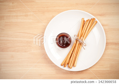 pack of breadsticks with ketchup dipping sauce in white dish on wood table 142366658