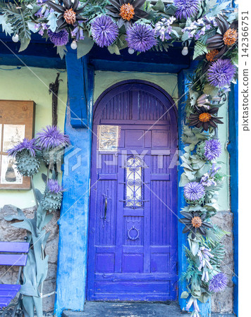 Kyiv, September 26, 2025, Vibrant purple door with floral garland on whimsical coffee shop facade, vintage blue wood Kyiv, September 26, 2025, Vibrant purple door with floral garland on whimsical coffee shop facade, vintage blue wood 142366751