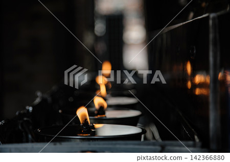 many candles in oil plate light up for people to offering or pray to buddha in Thai's temple 142366880