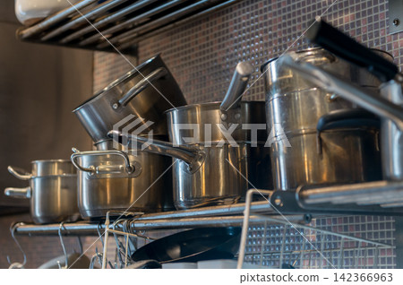 Stainless steel pots neatly arranged on kitchen shelves in restaurants and kitchens. Stainless steel pots neatly arranged on kitchen shelves in restaurants and kitchens. 142366963